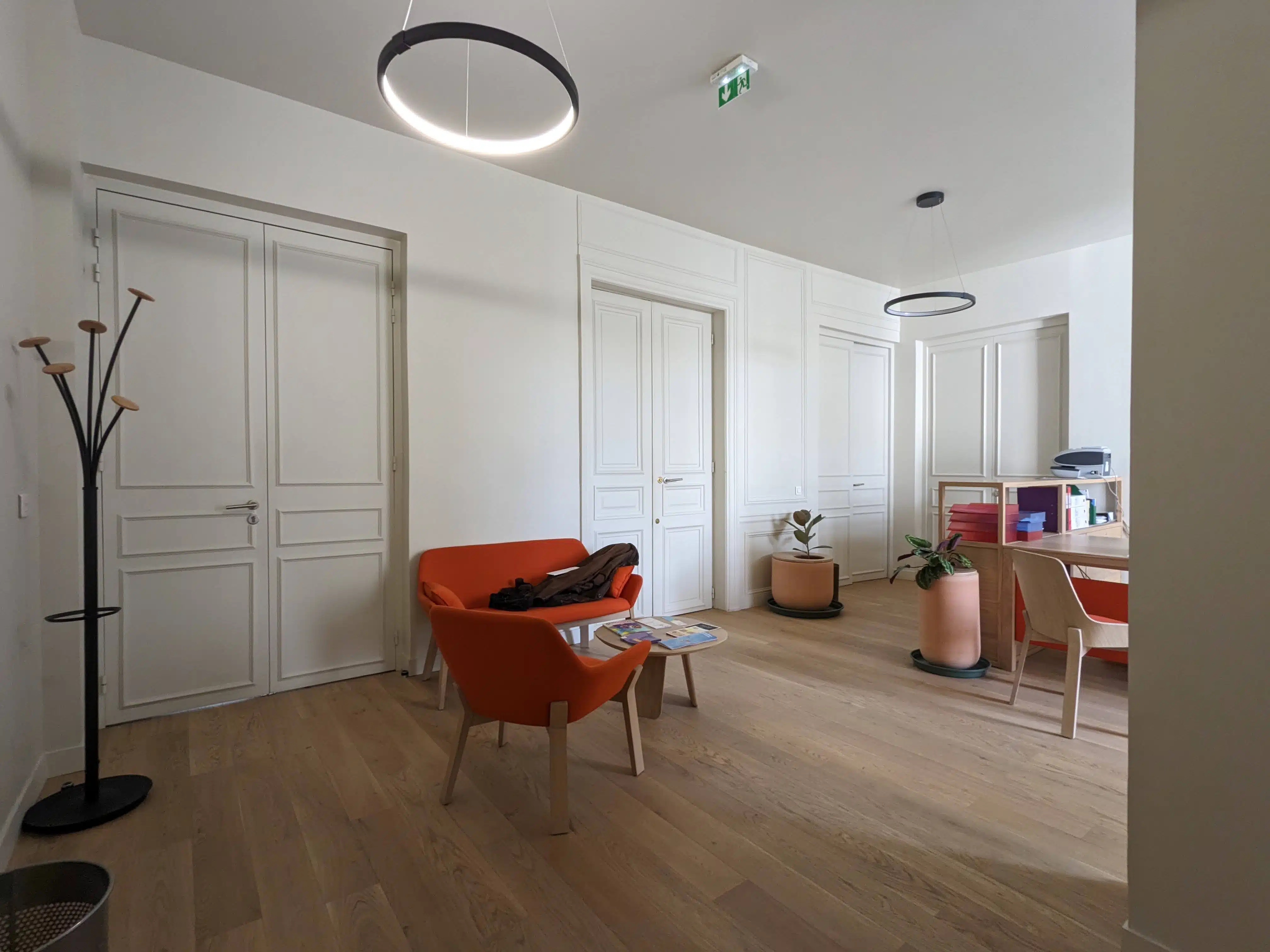 Rénovation de bureaux : l'espace accueil transformé : le salon d'accueil, porte-manteaux, luminaire